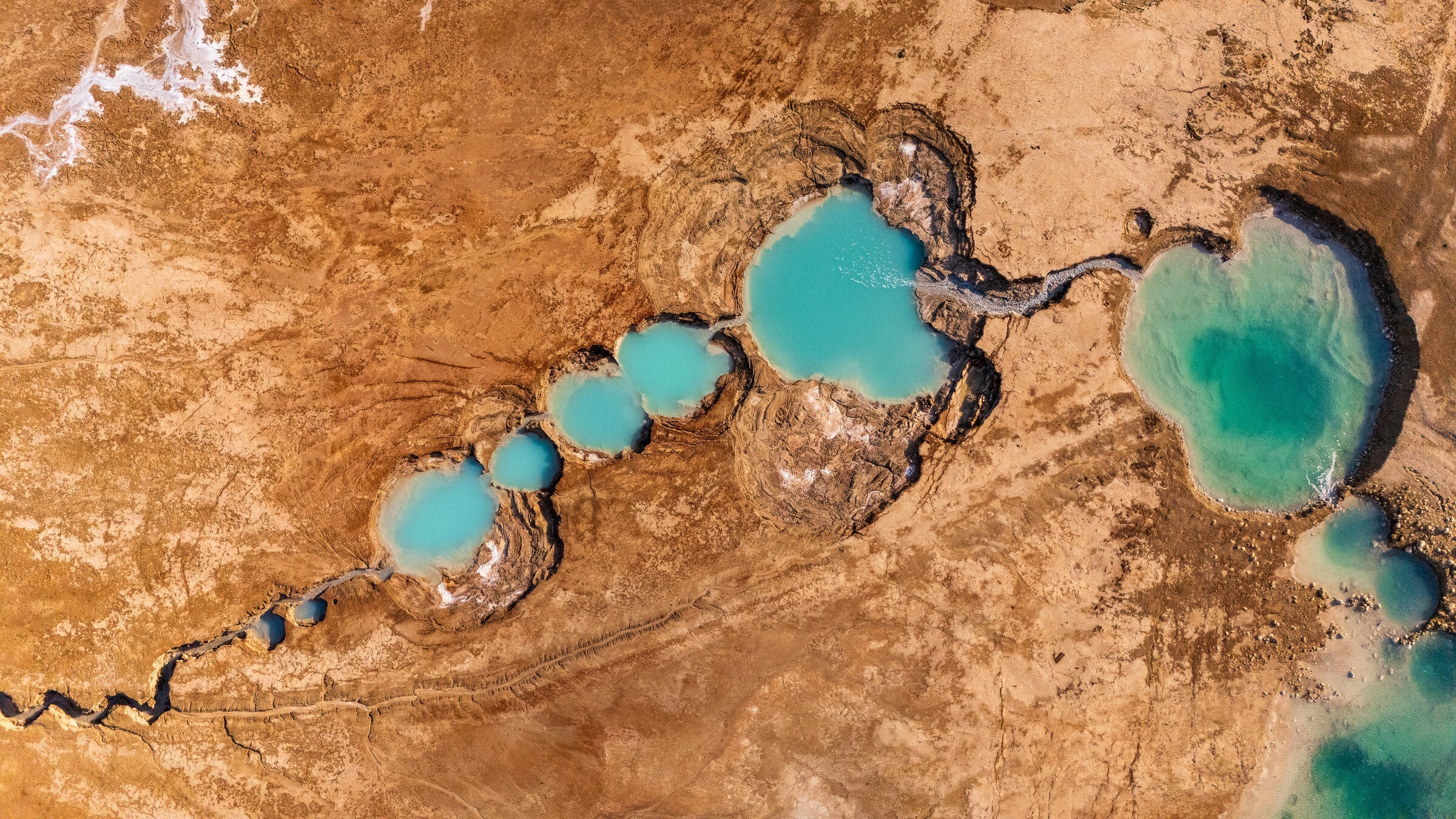 Aerial view of turquoise sinkholes along the Dead Sea shoreline
