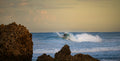 Wave breaking around a weathered rock, fine art print
